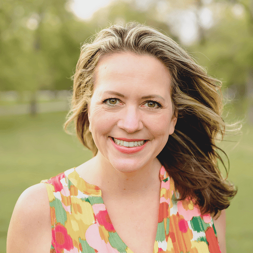 Smiling woman with blonde hair outdoors in a park, wearing a colorful floral dress. Captures natural beauty and positive energy perfect for wellness or lifestyle branding.