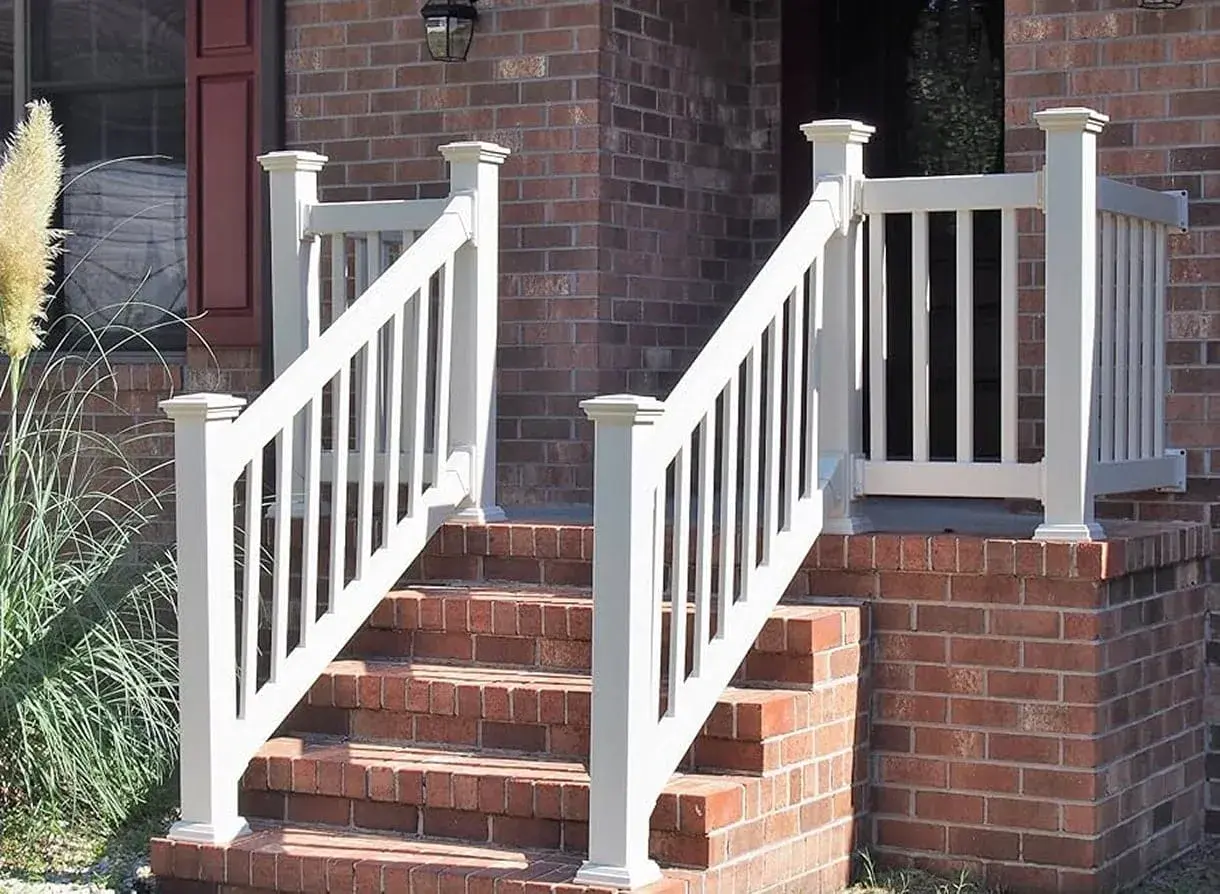 White vinyl railing installed on brick stairs leading to a residential front porch, enhancing safety and curb appeal.